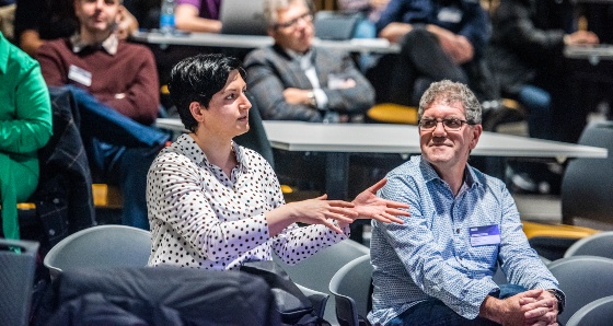 Two conference attendees sit together and chat.